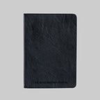 A black textured leather journal with 'THE GROUNDED MAN JOURNAL' embossed on the front, shown against a solid gray background.