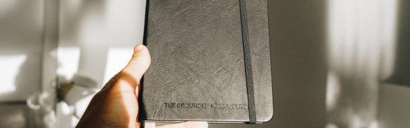 Man holding a journal called the Grounded Man Journal